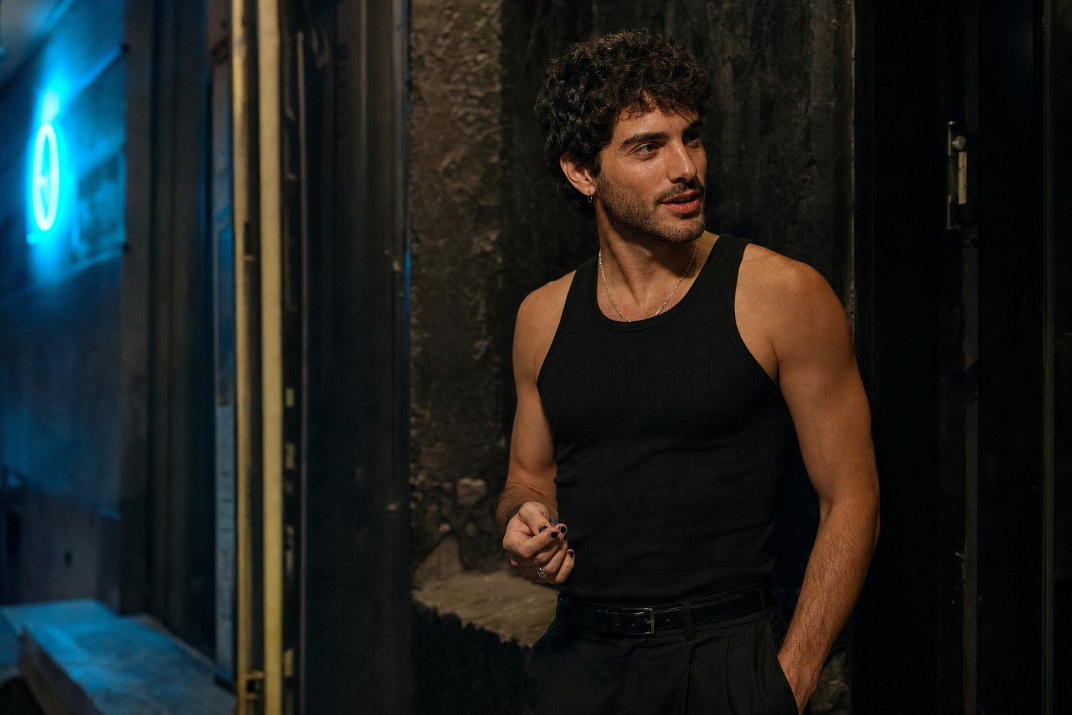 Man wearing a fitted black tank top outside a bar at blue hour