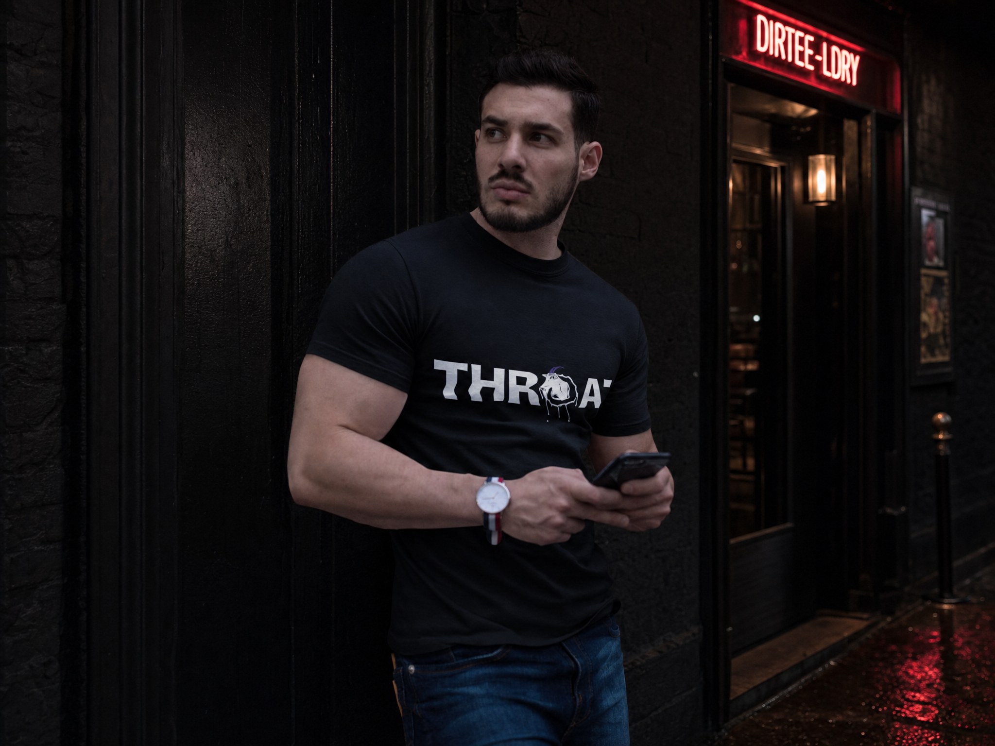 Man in a black THROAT tee waiting outside the DIRTEE-LDRY club entrance