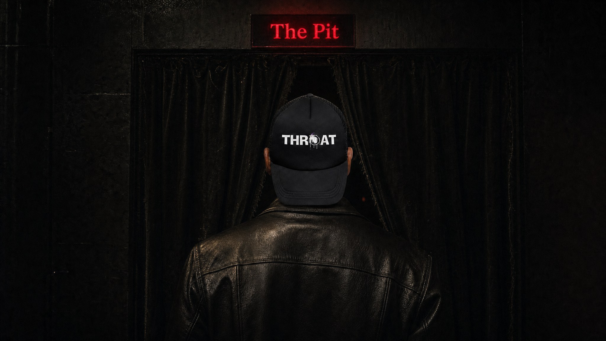 Man in a black trucker hat and leather jacket in a dark venue entrance