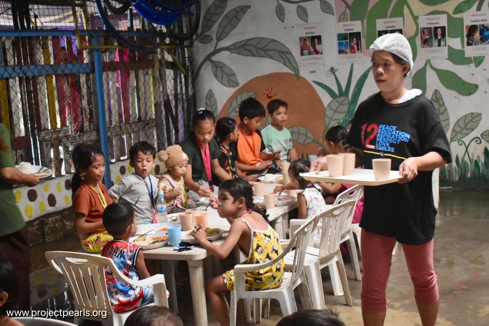 Children sharing a meal with Project PEARLS staff