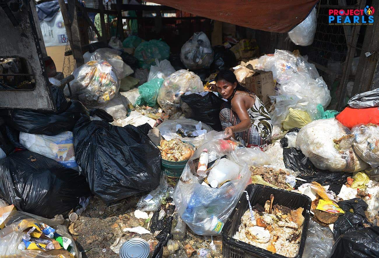 A woman beside bags of refuse in a community affected by food insecurity