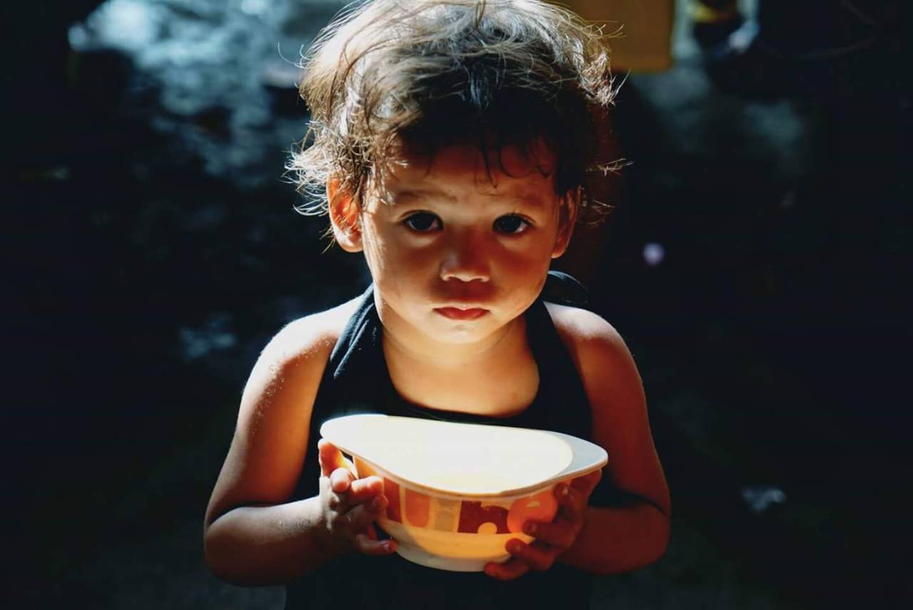 Child holding a bowl of food