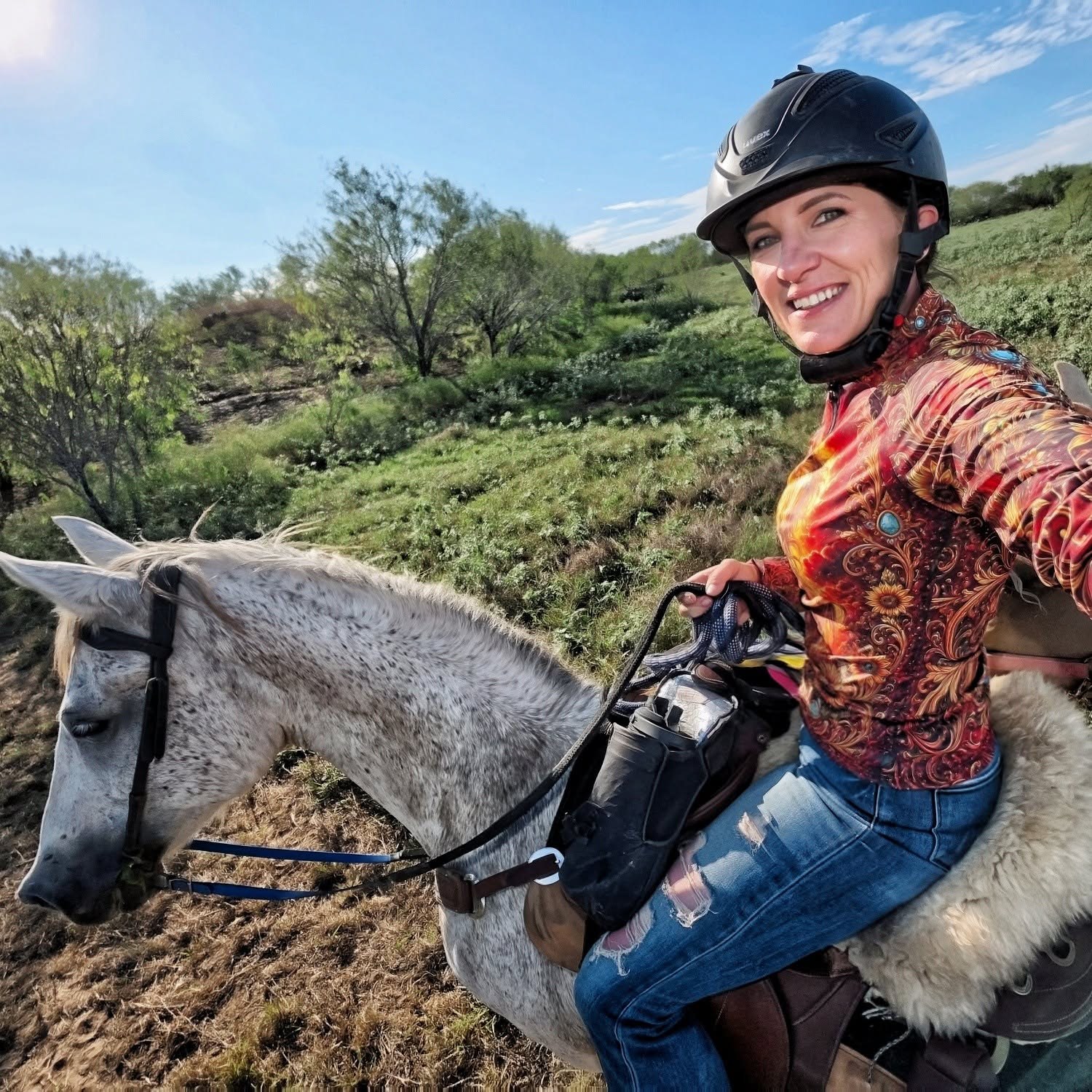 Mounted rider in an illustrated shirt with a fluffy cream seat cover visible on the saddle