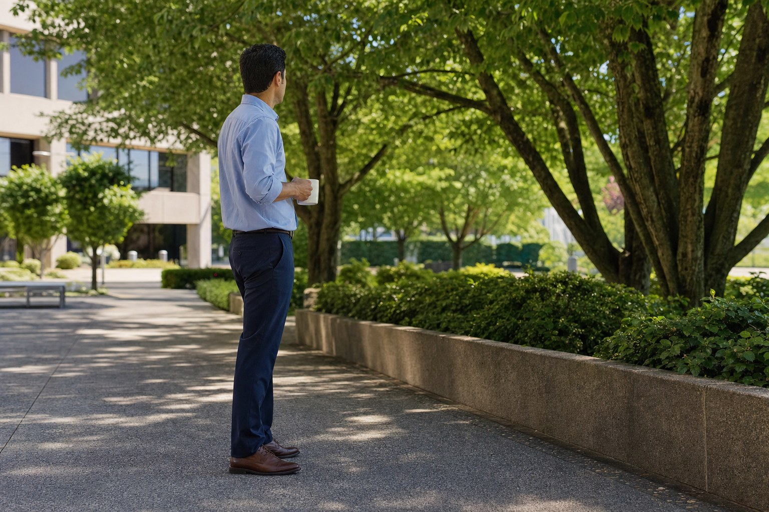 Office worker taking a quiet break outside beneath leafy trees
