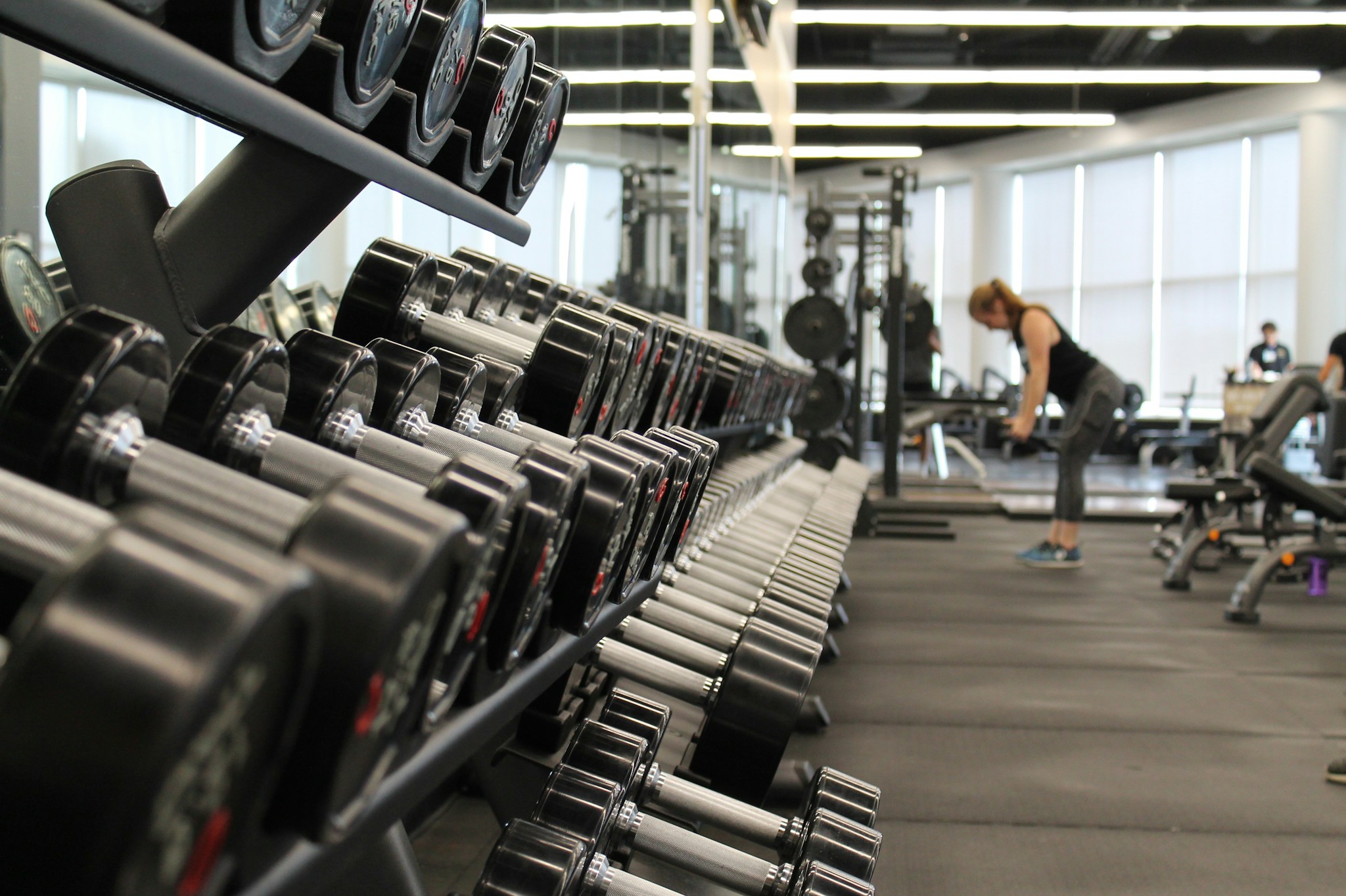 Lifter seated in a strength gym, reviewing a training notebook after dumbbell work