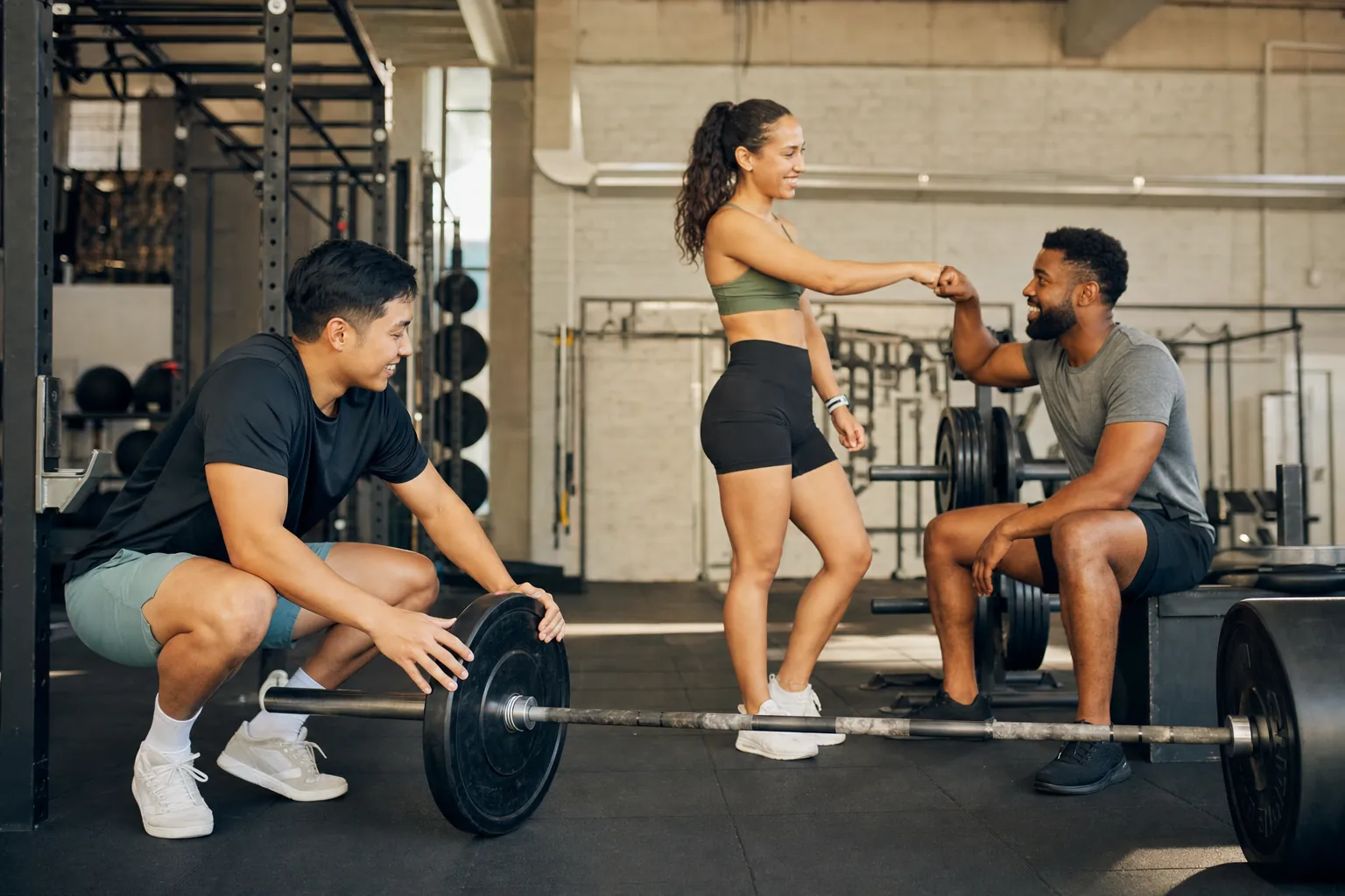 Three friends sharing a moment between sets in a gym