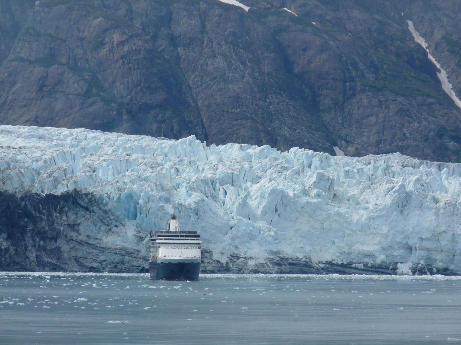 Cruise ship sailing in Glacier Bay beneath a tidewater glacier