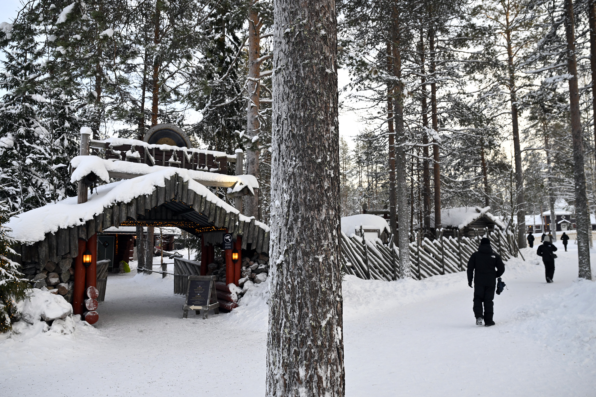 Snow-covered woodland path and timber entrance at Santa Claus Village