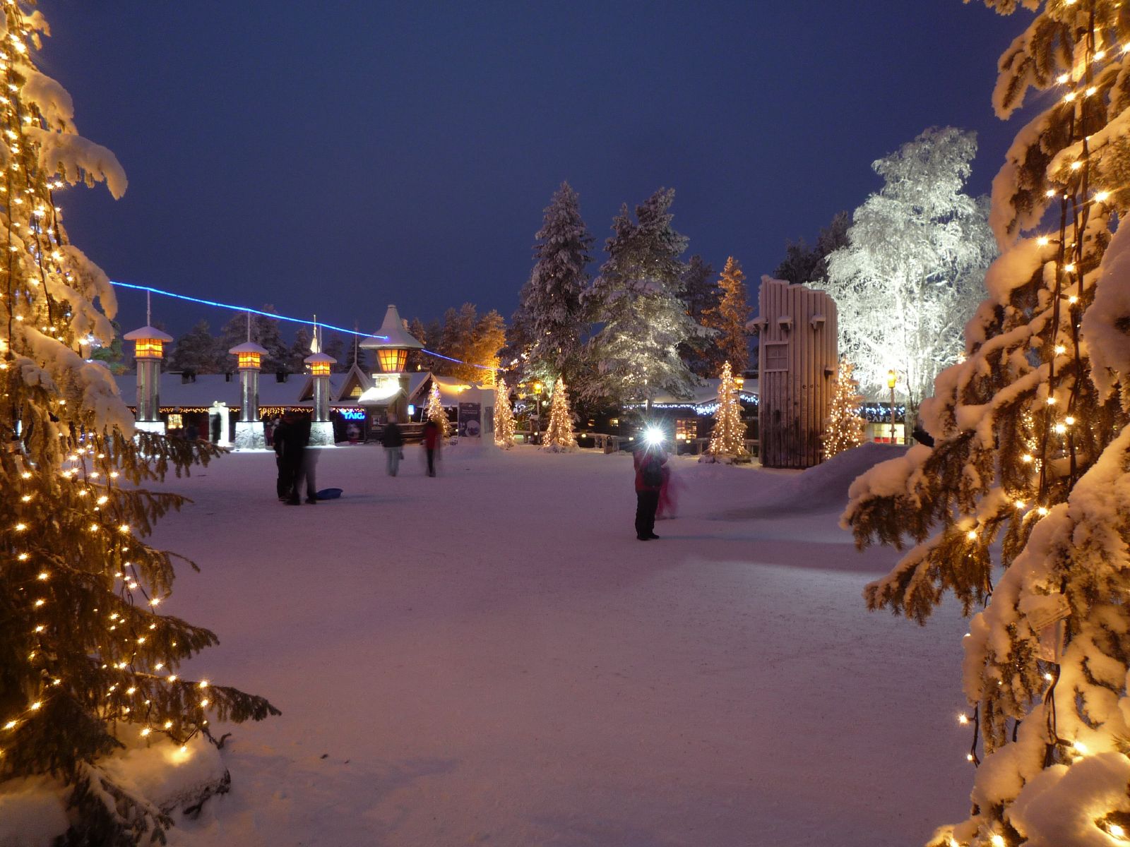 Illuminated Christmas trees and snow-covered paths at Santa Claus Village in Rovaniemi
