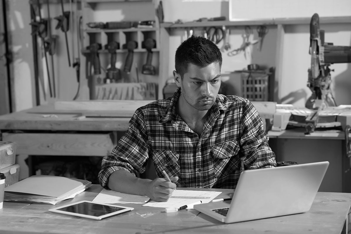 Workshop owner reviewing business paperwork at a workbench