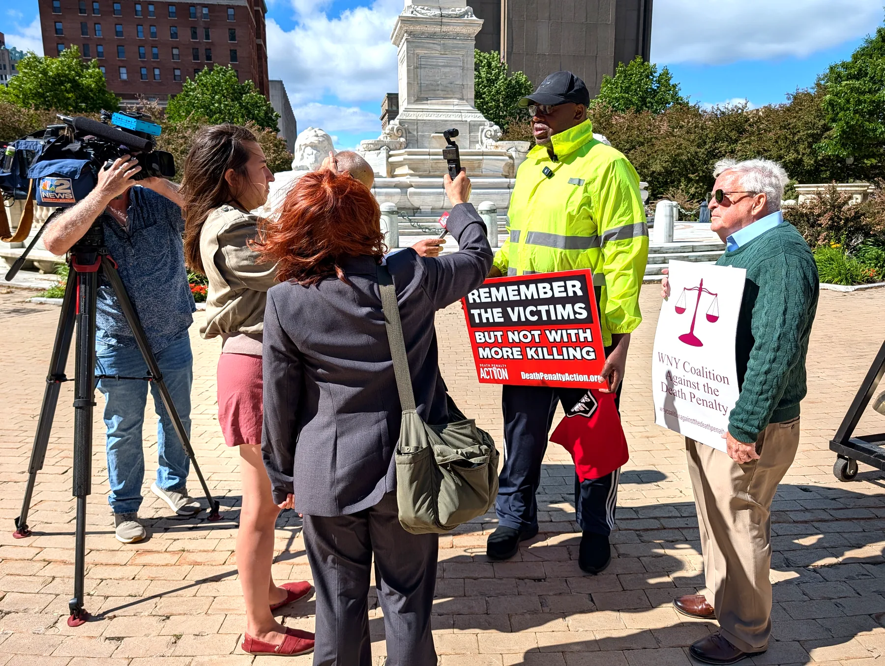 Murray Holman and Paul McQuillen speaking with local press beside signs opposing the death penalty