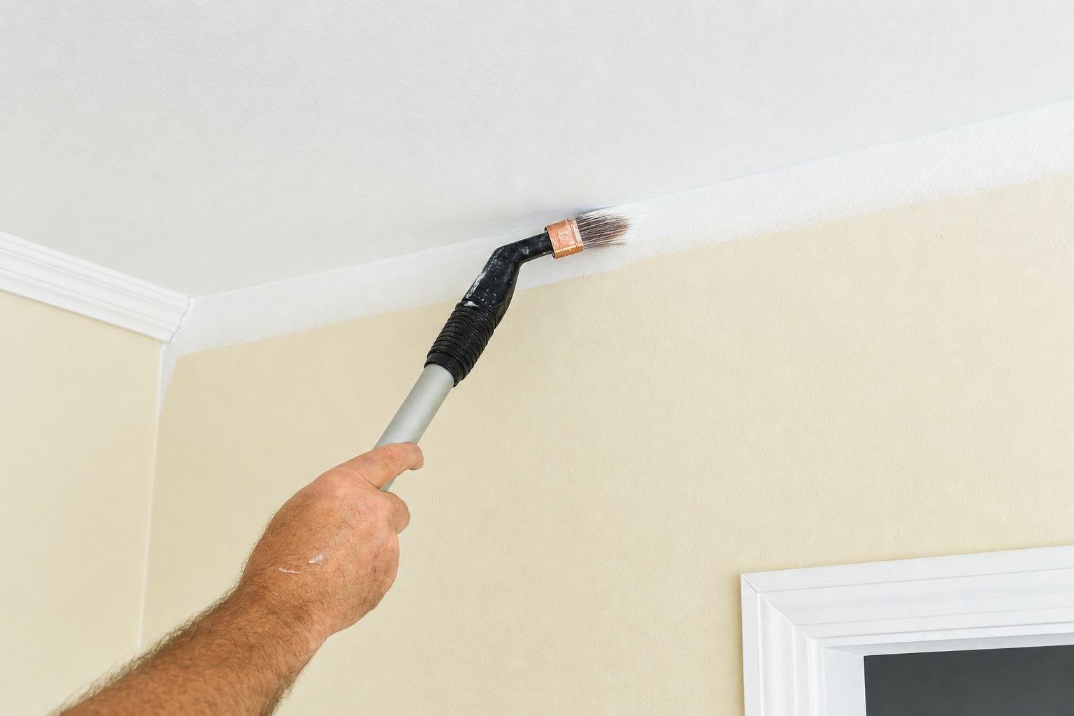 Painter cutting a clean line where a ceiling meets a wall