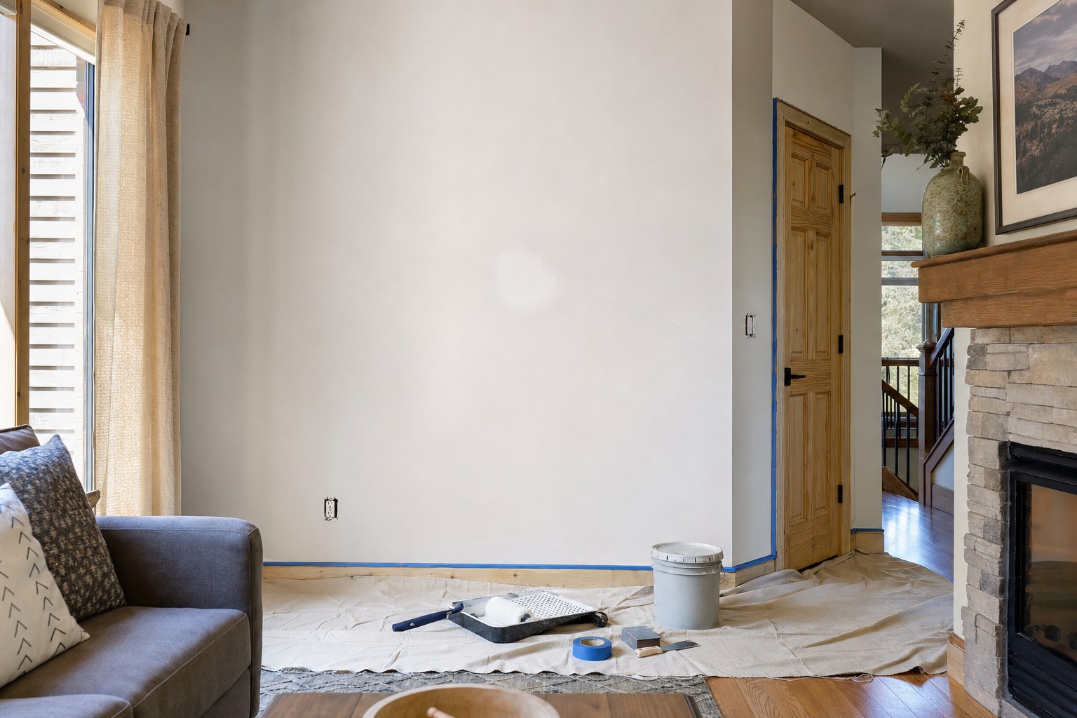 Living room wall prepared for painting with floor protection and painting tools in place