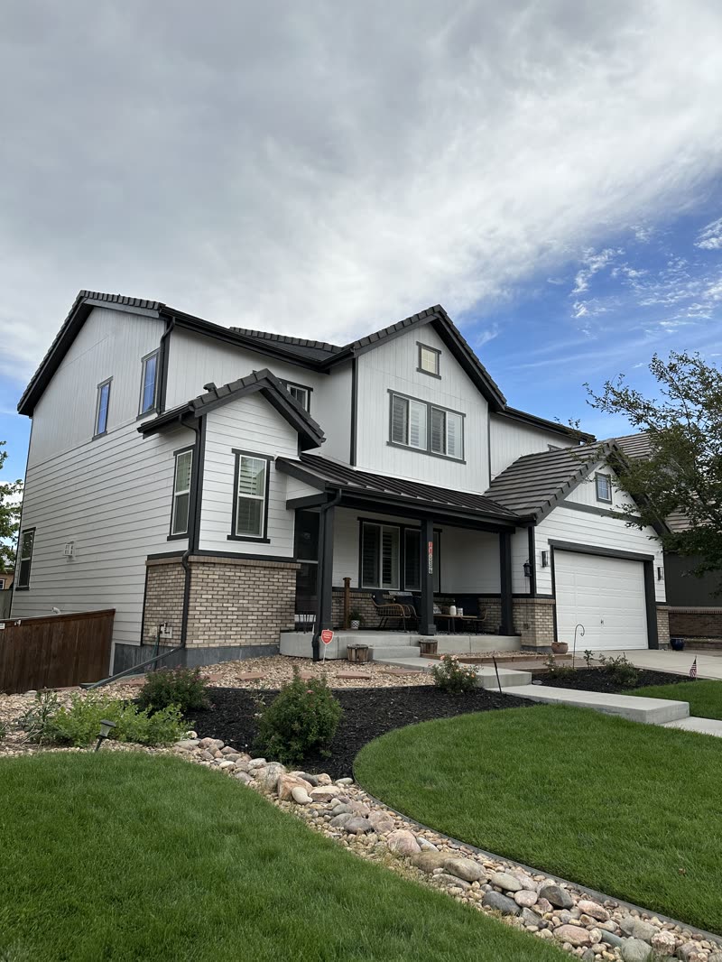 Finished white exterior with dark trim and landscaped front yard