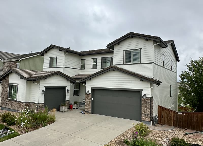 Finished white two-story home exterior with dark garage doors