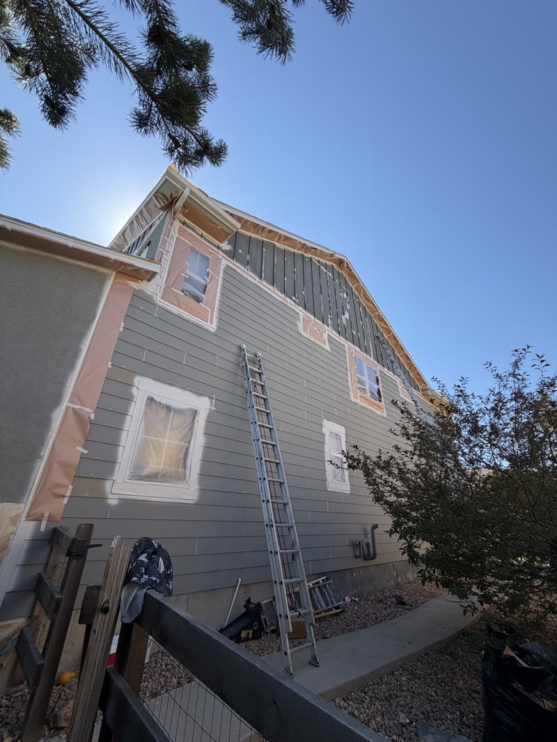 Exterior home preparation with protected windows and ladder