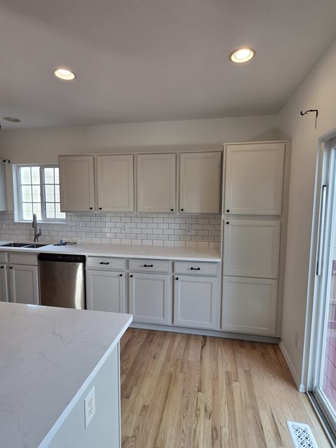 Finished white kitchen cabinetry and wood flooring