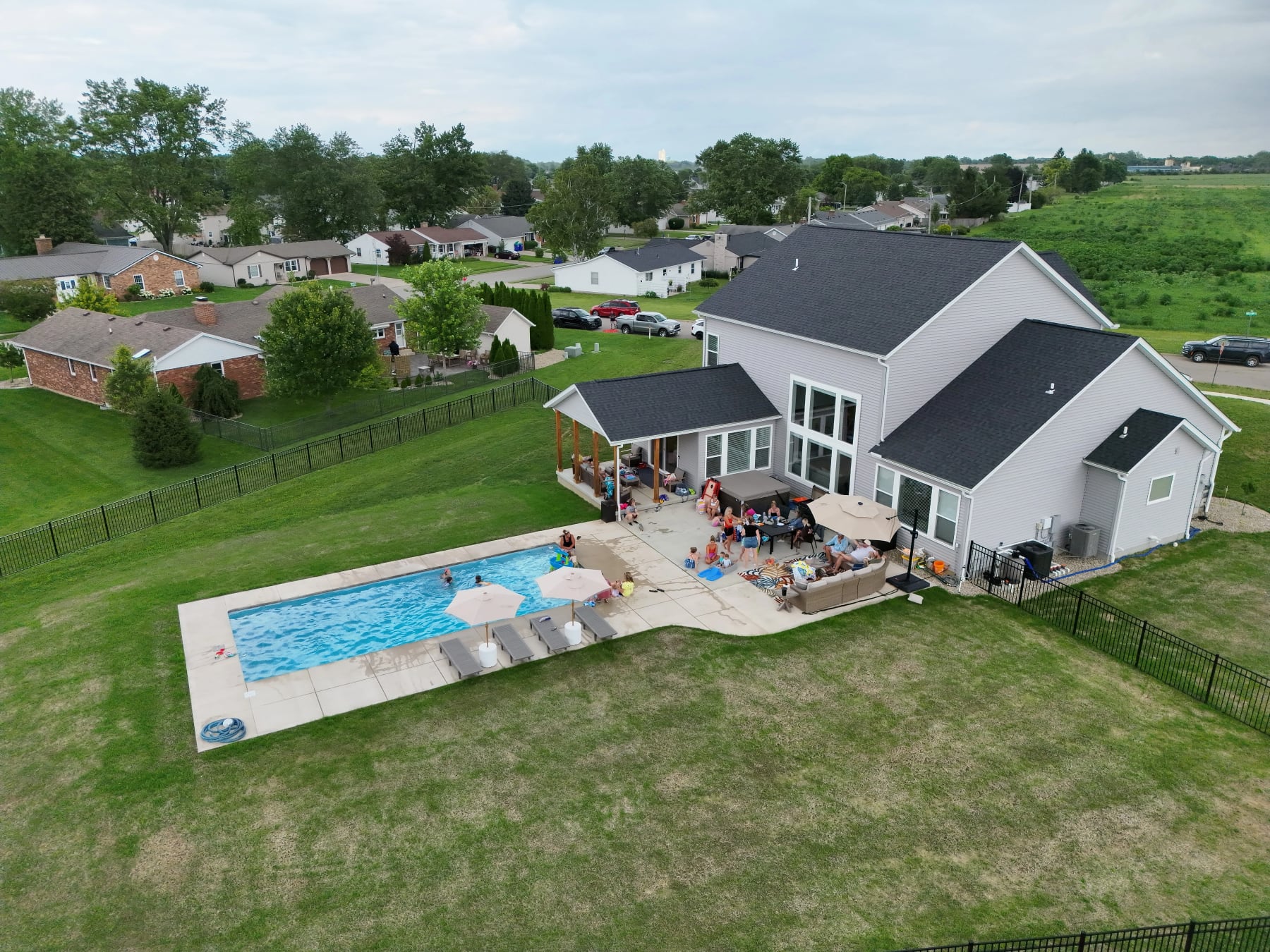 Aerial view of a home with a backyard pool and outdoor gathering space