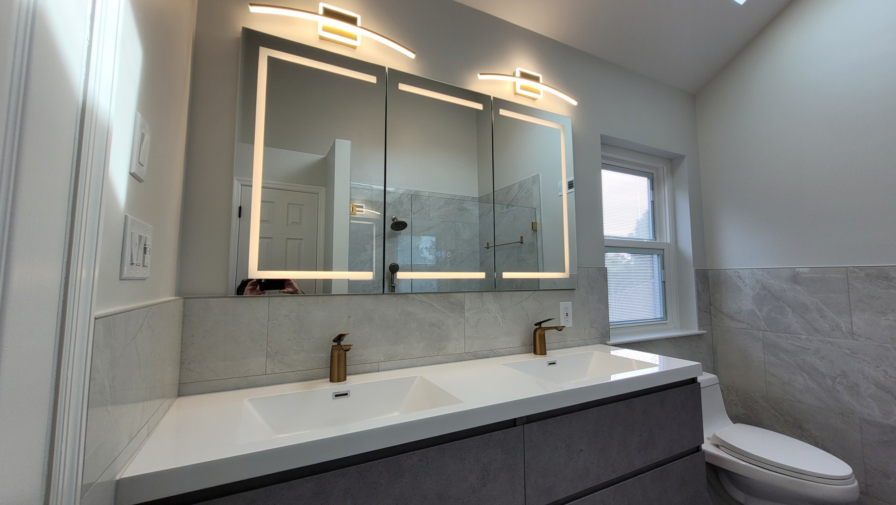 Renovated Collegeville bathroom with a gray double vanity and illuminated medicine cabinet