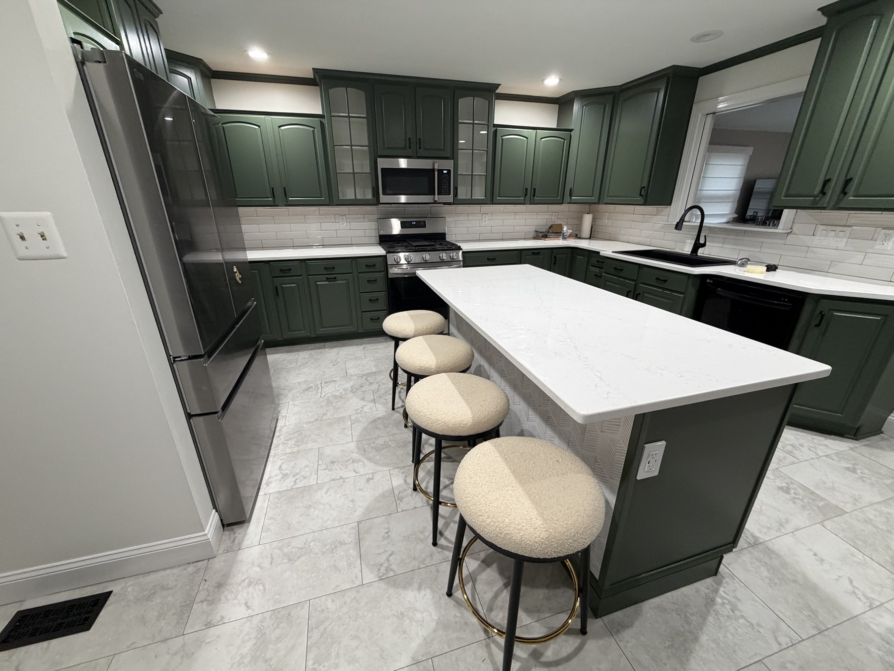 King of Prussia kitchen with existing cabinets repainted green, a custom-trimmed island, light countertop, and four stools