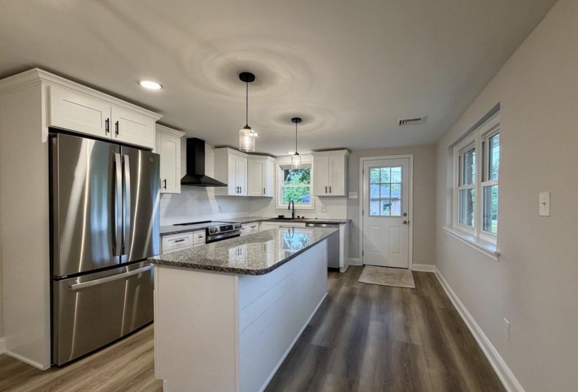 Pottstown kitchen with white cabinets, a granite-topped island, pendant lights, stainless steel appliances, and new flooring