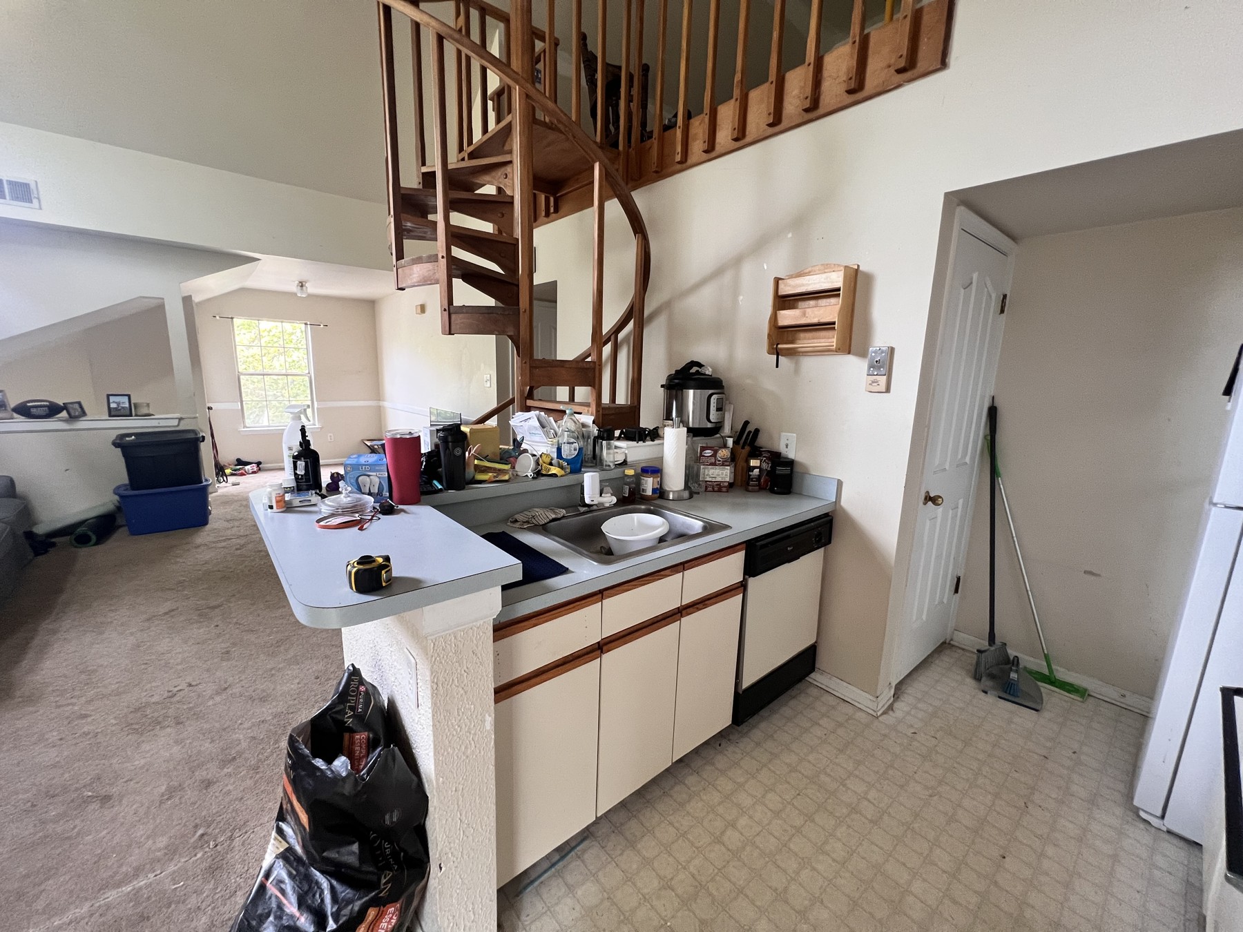 Original kitchen sink and cabinets below a raised counter and half wall beside the spiral staircase
