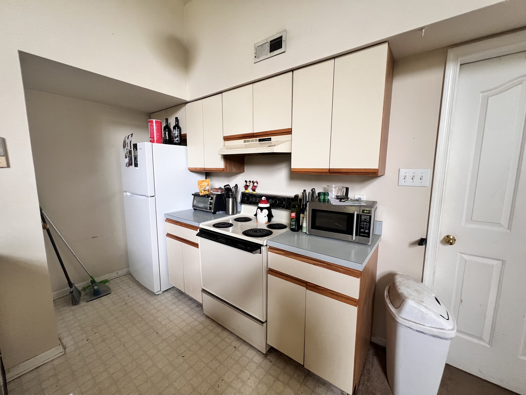 Original Royersford kitchen with cream cabinet doors, wood trim, gray countertops, and white appliances