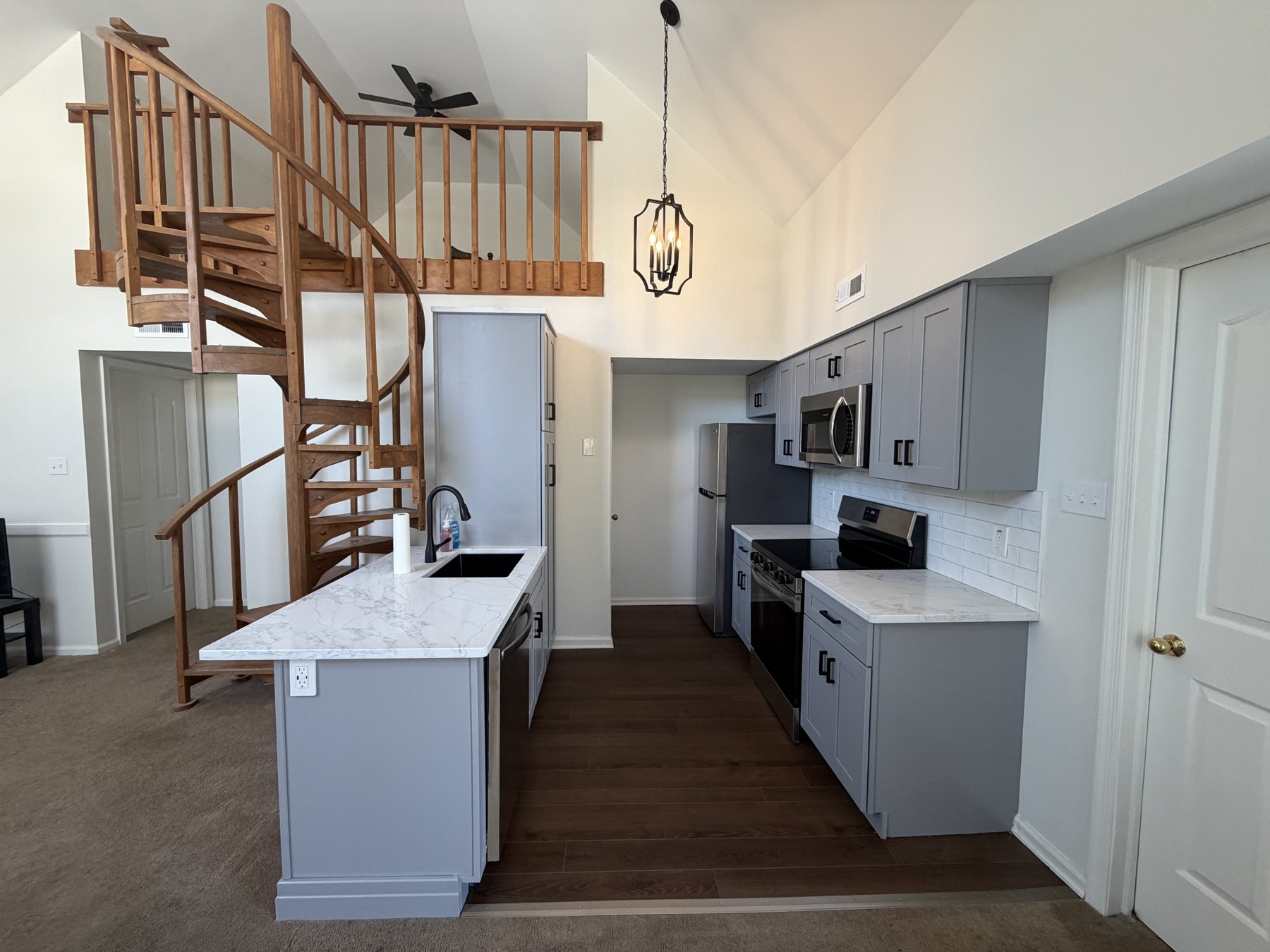 Renovated Royersford kitchen with gray cabinets, quartz countertops, black hardware, and a spiral staircase beside the kitchen