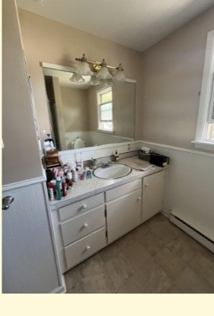 Main bathroom before the refresh with a white single-sink vanity, rectangular mirror, and older light fixture