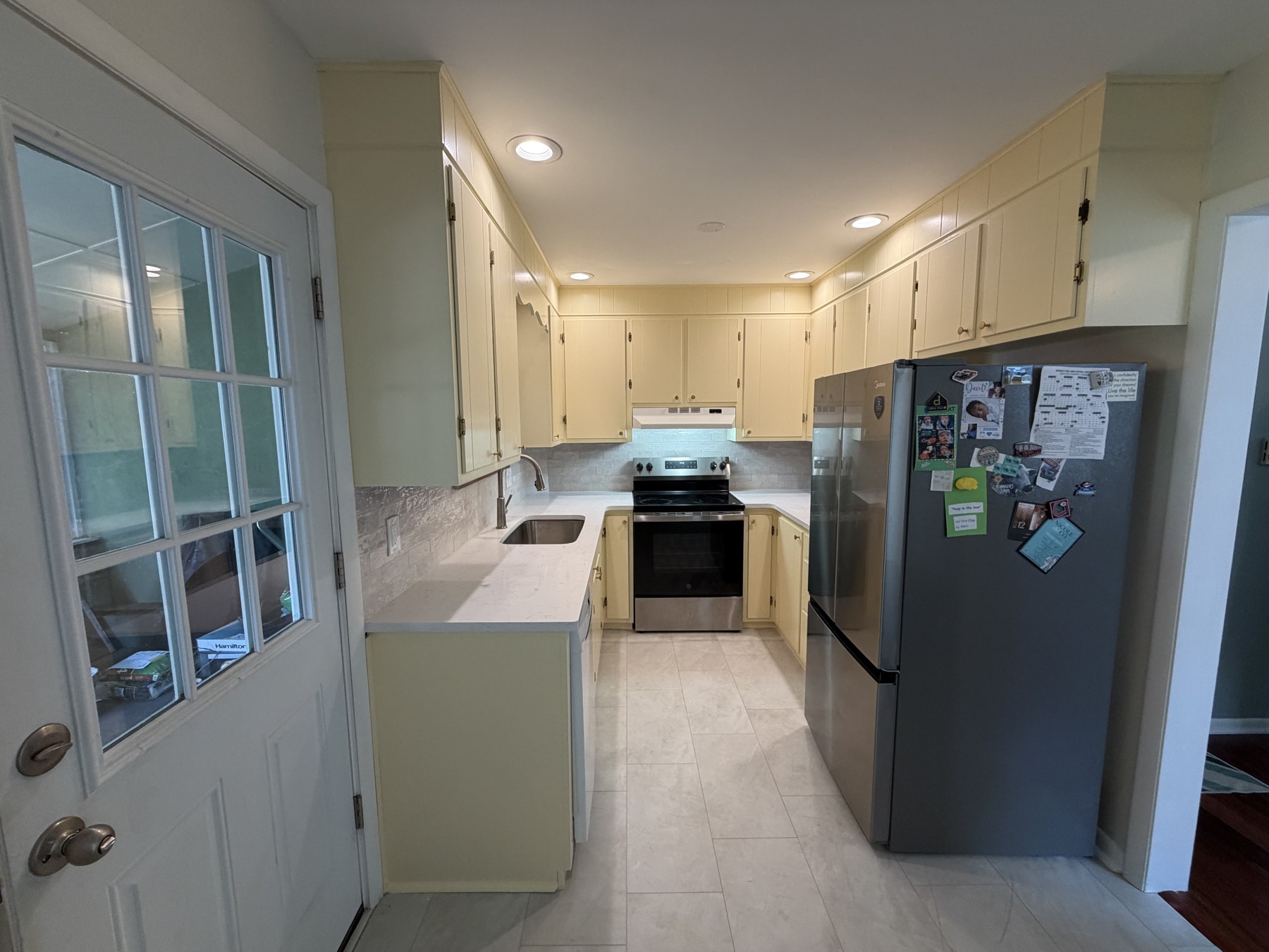 Royersford kitchen with pale yellow repainted existing cabinets, light countertops, tile backsplash, and stainless steel appliances