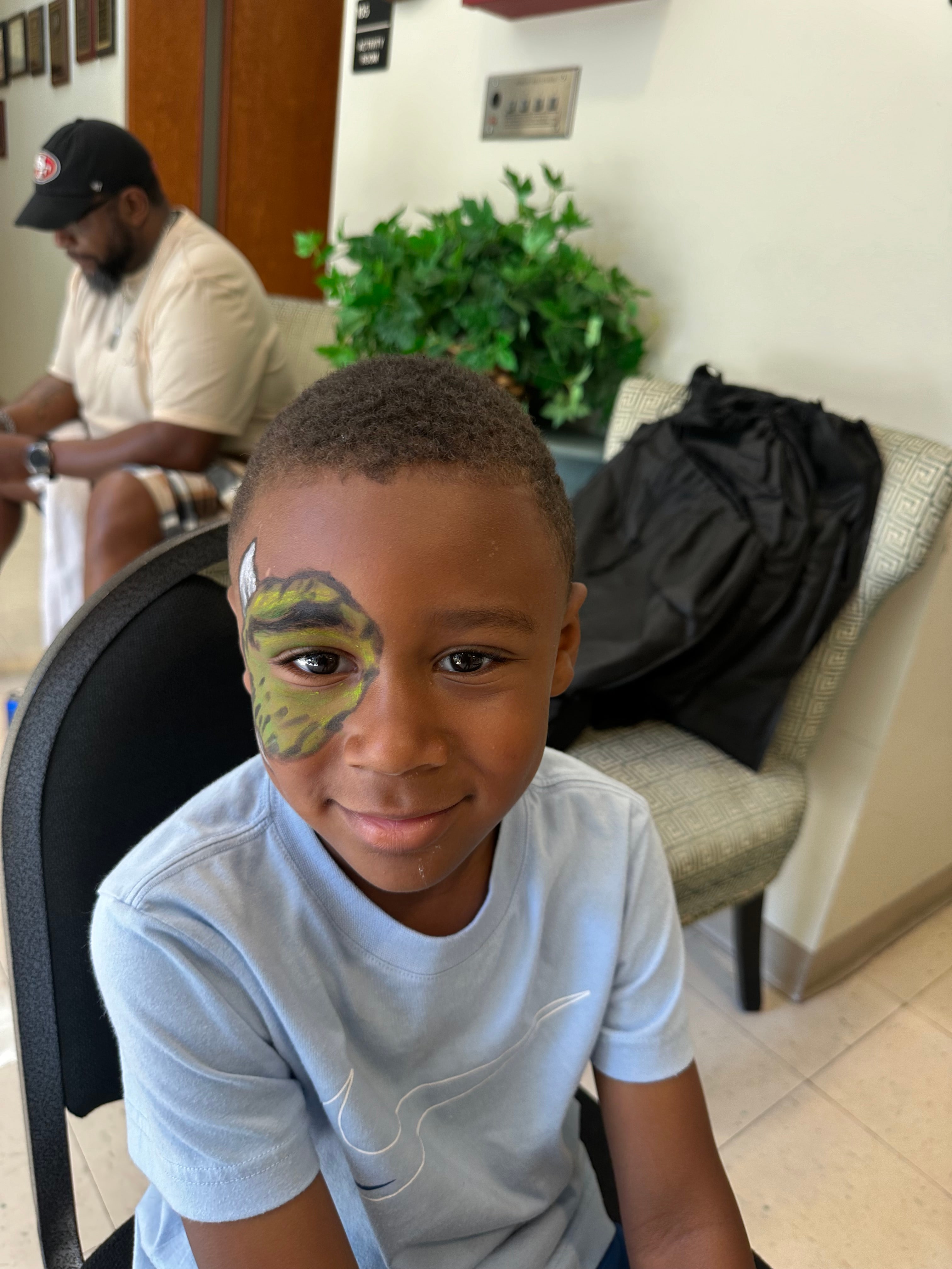 Child wearing colourful floral face paint by Desiree Tatum