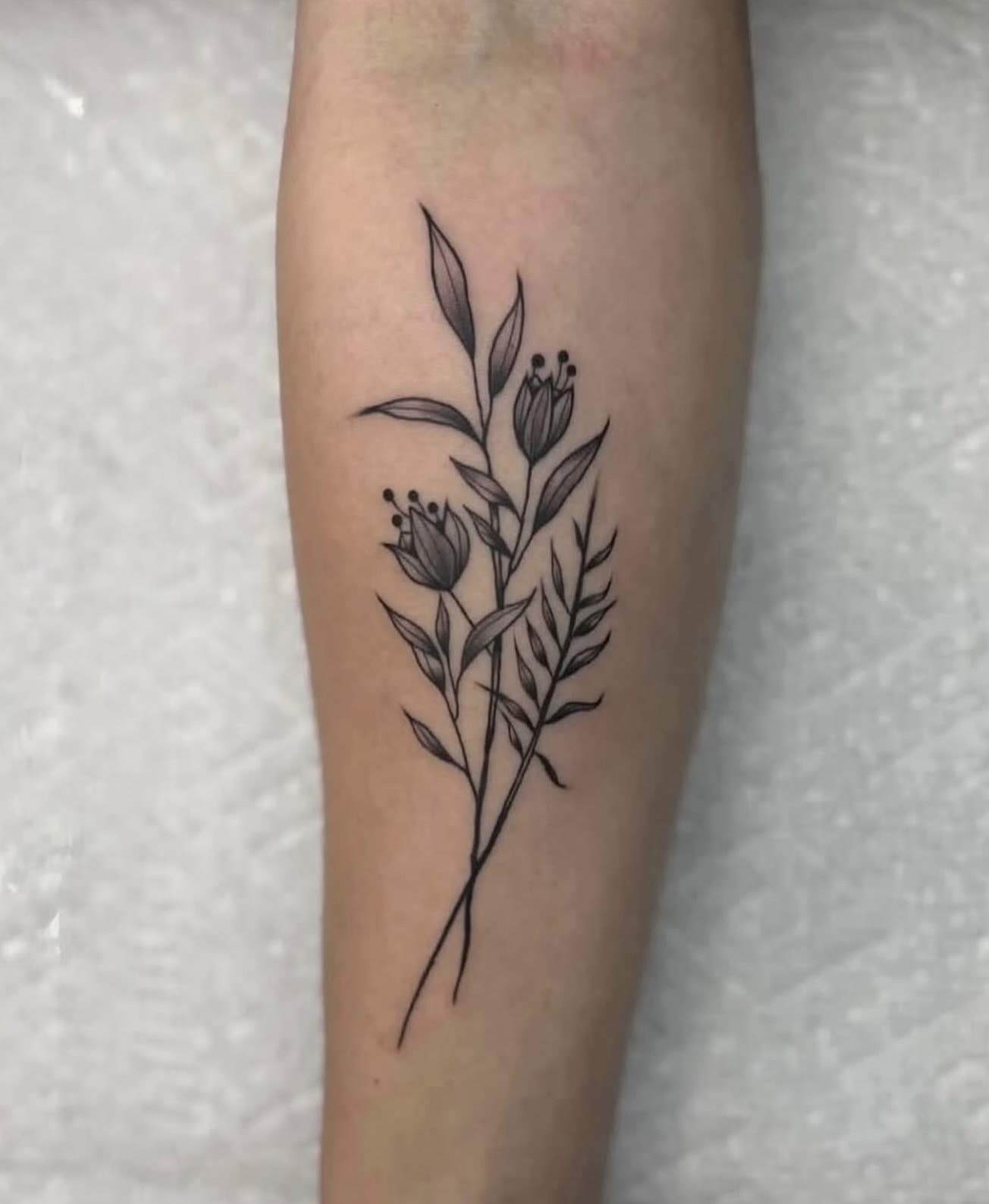 Botanical black and gray tattoo placed along an arm