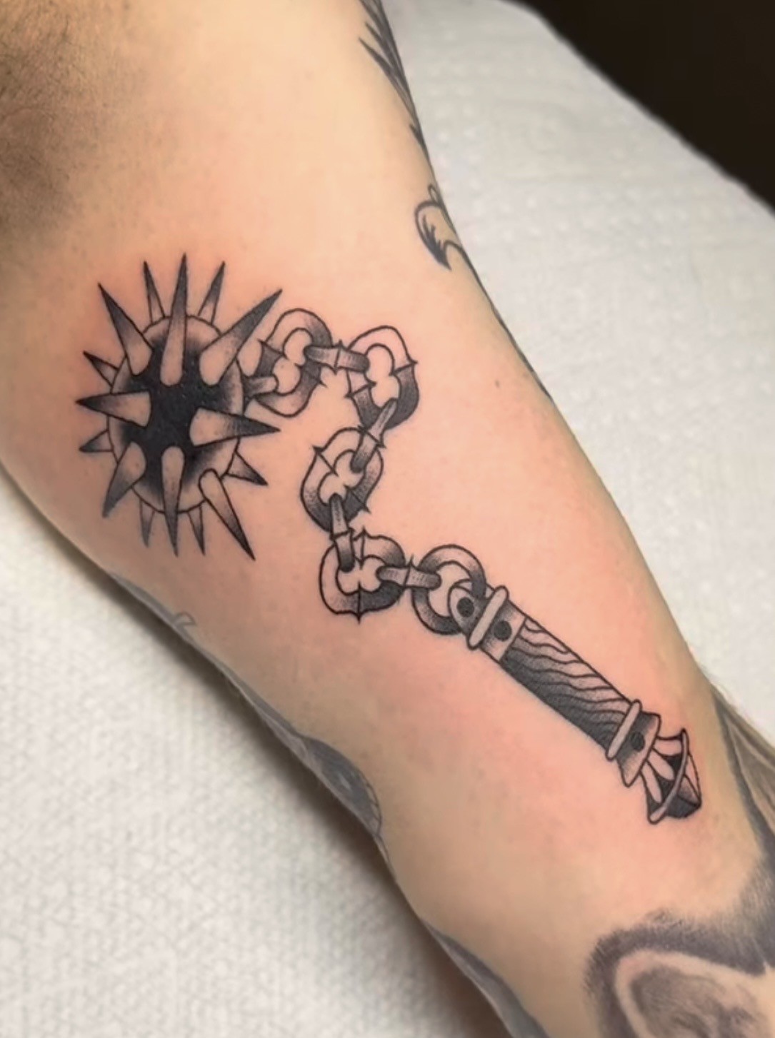 Black and gray dagger tattoo with clear negative space on an arm