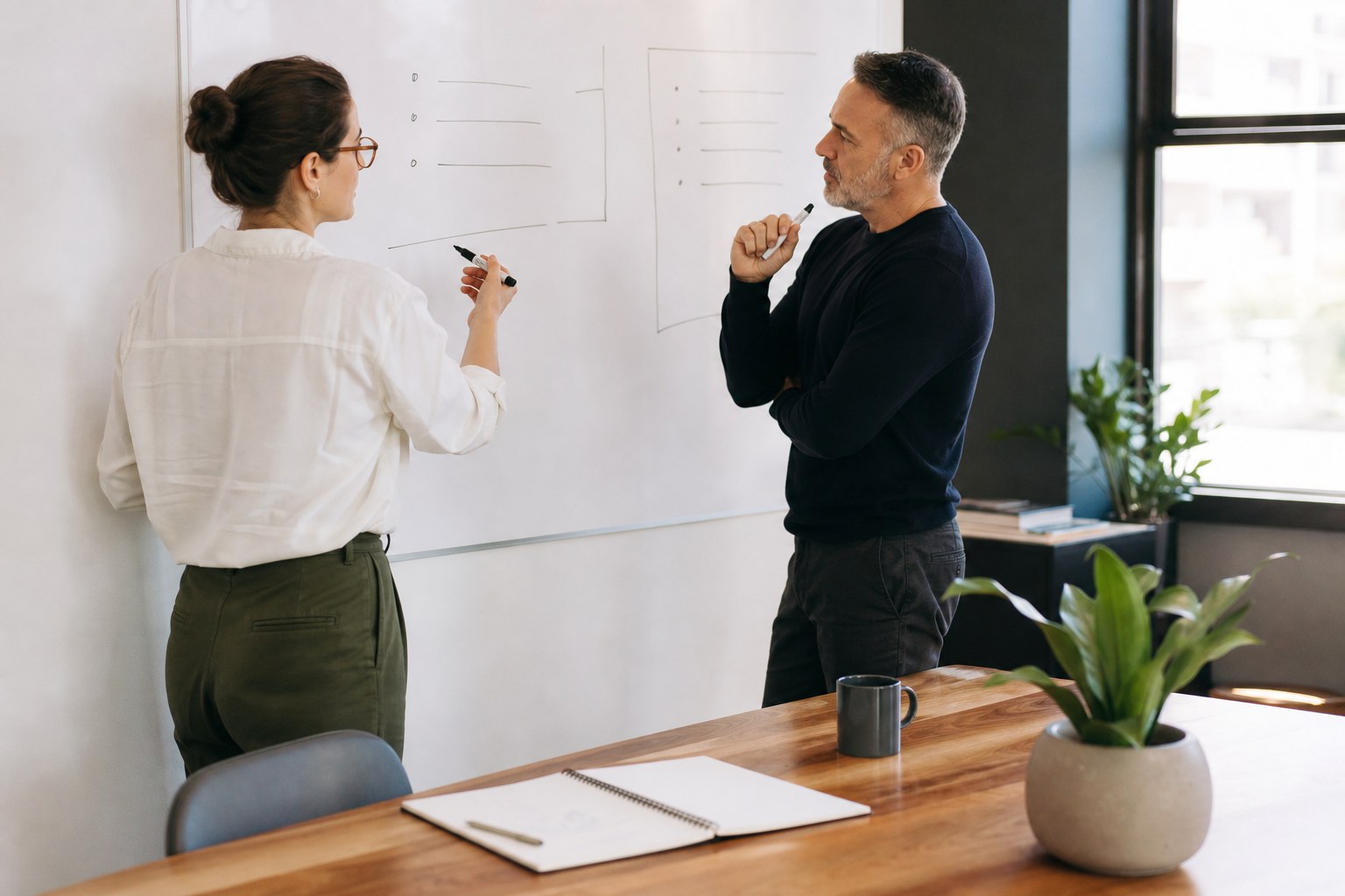 Two colleagues planning a structured interview at a whiteboard