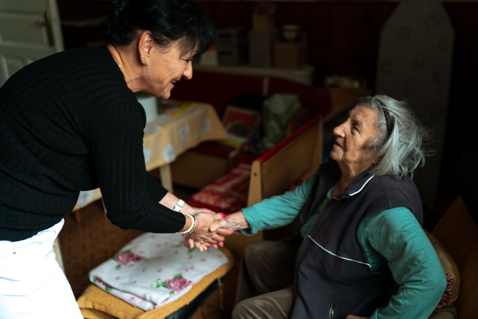 Caregiver greeting a senior woman with a warm handshake