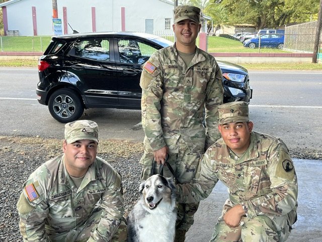 Three U.S. Army service members with a dog