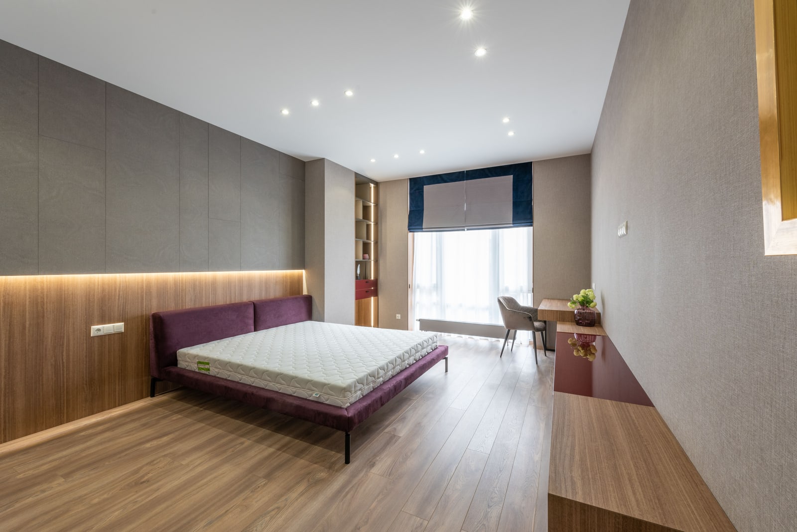 A bright modern bedroom with a white mattress on a wood-framed bed.