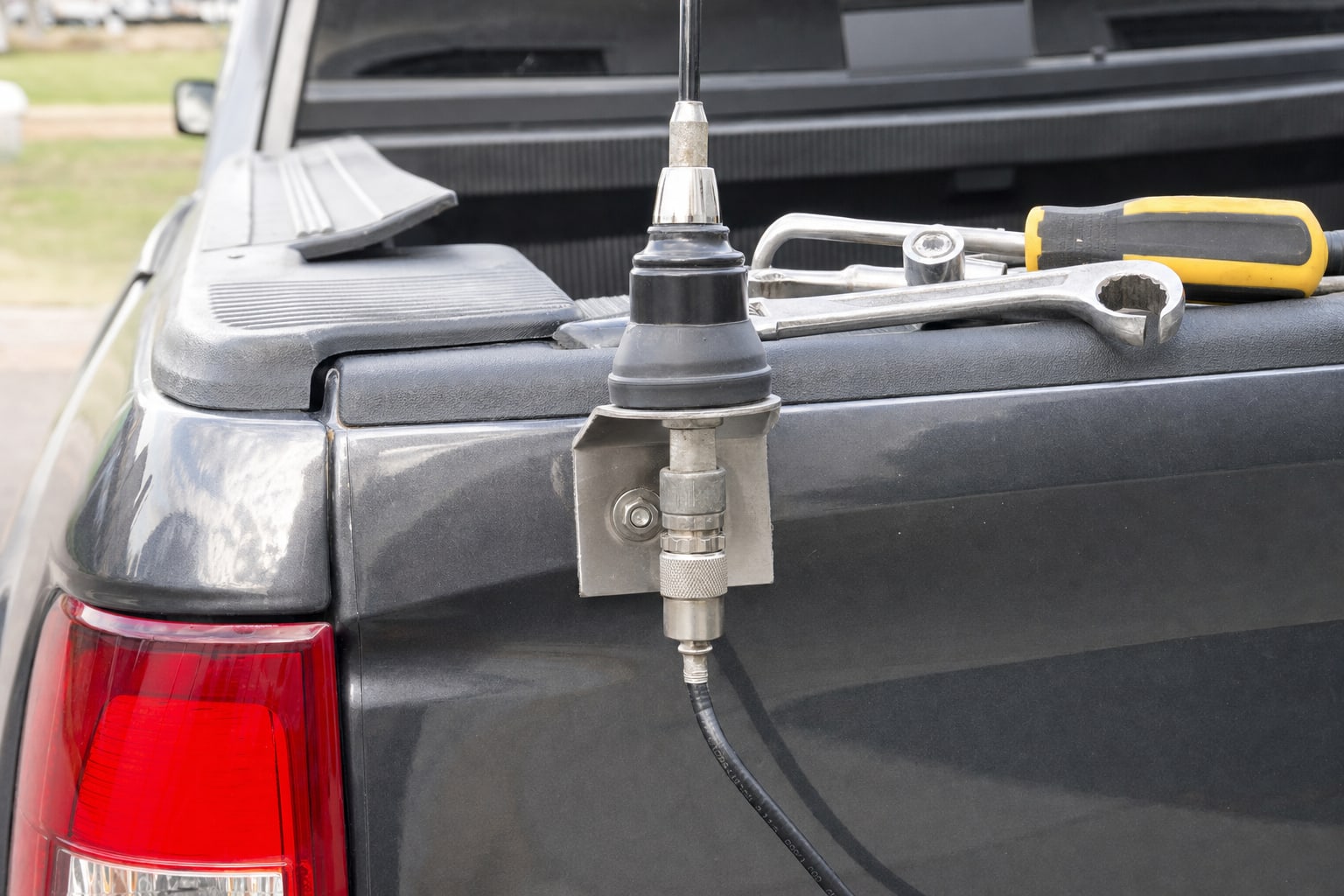 CB antenna mount, coax connector and mounting hardware inspected on a pickup truck bed rail