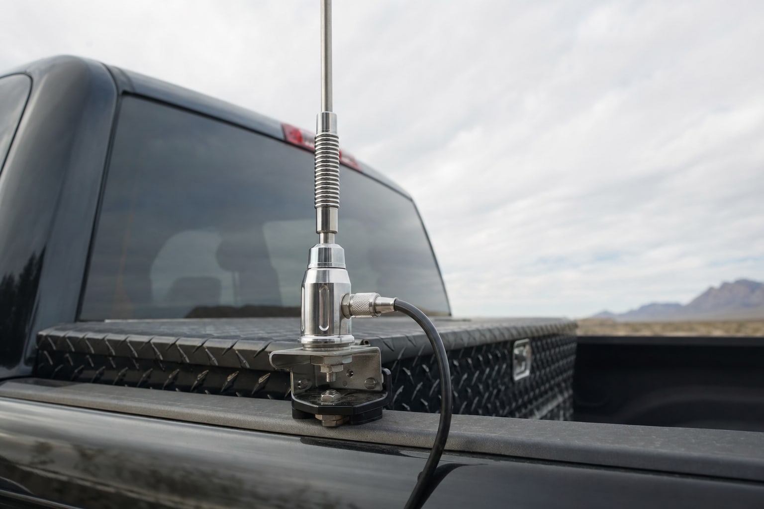 CB antenna mounted on the bed rail of a pickup truck