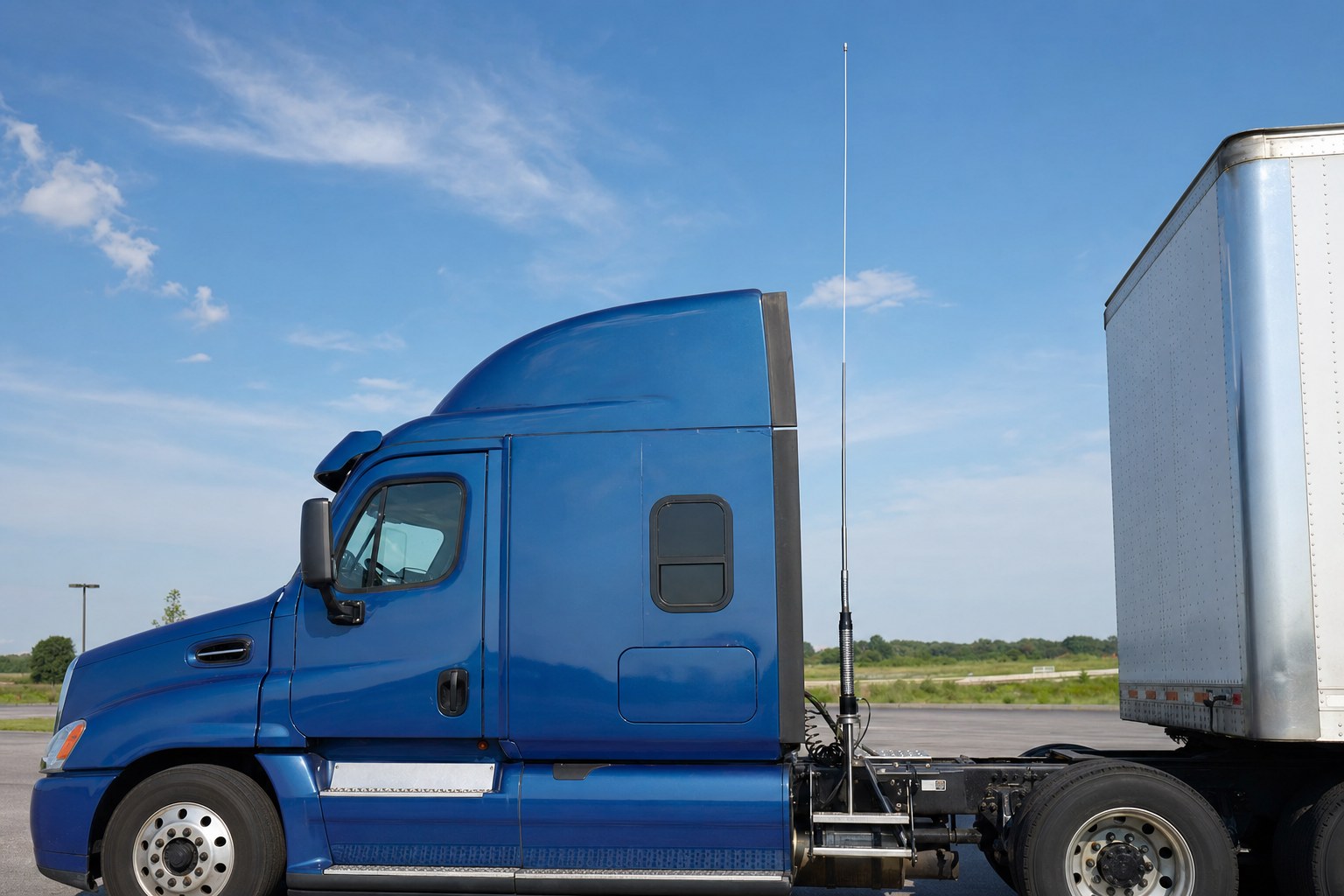 Tall CB antenna mounted behind the cab of a semi truck with clear space around it