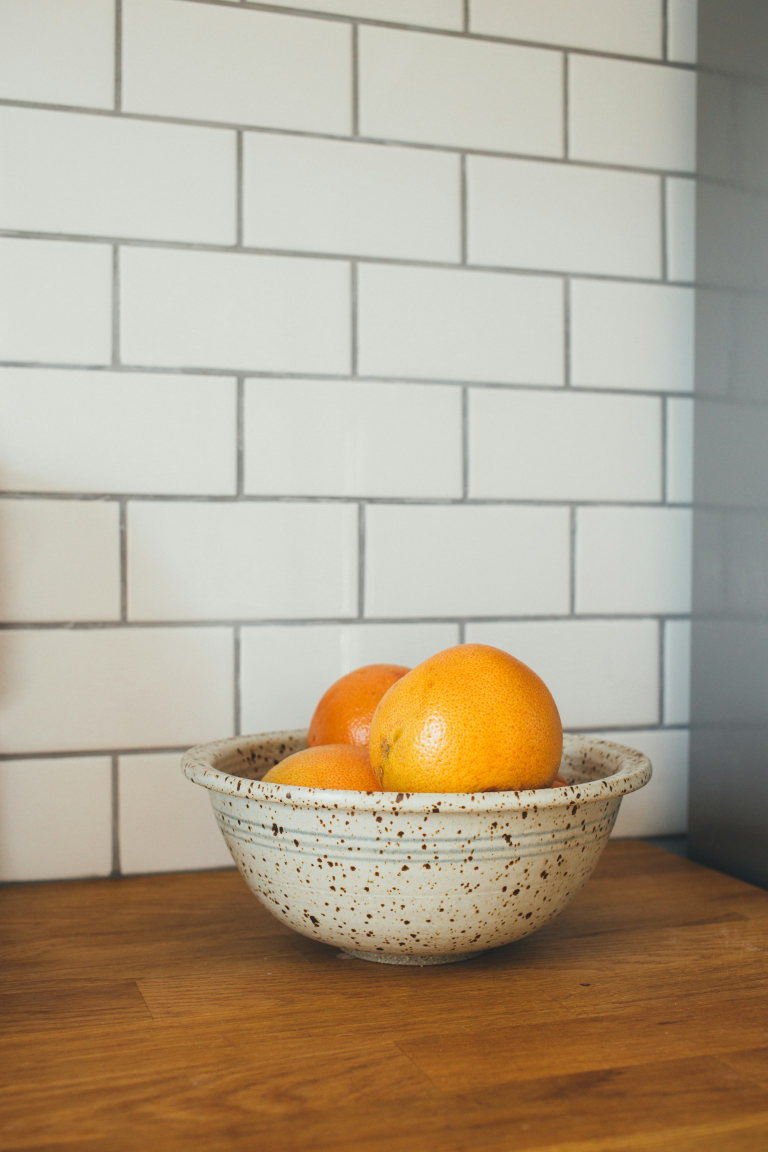 Oranges in a ceramic bowl on a clear kitchen counter