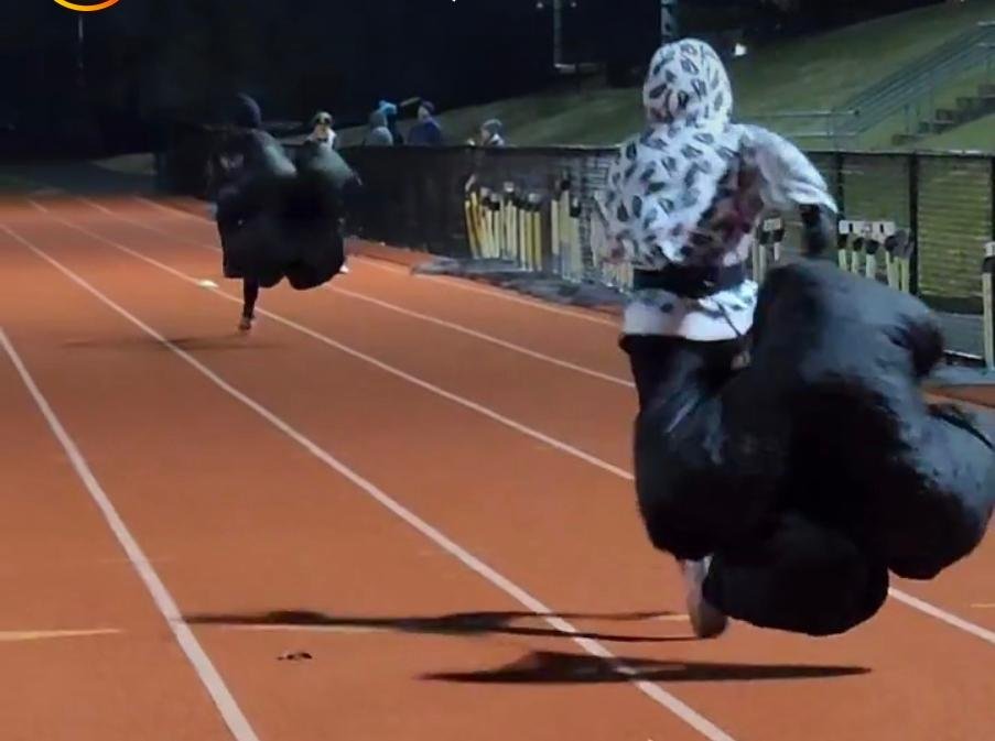 Athletes completing a resisted running drill on a track