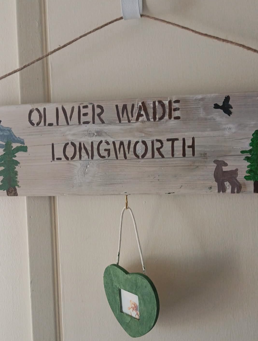 Hand-painted wooden family name sign displayed above a green heart-shaped photo holder