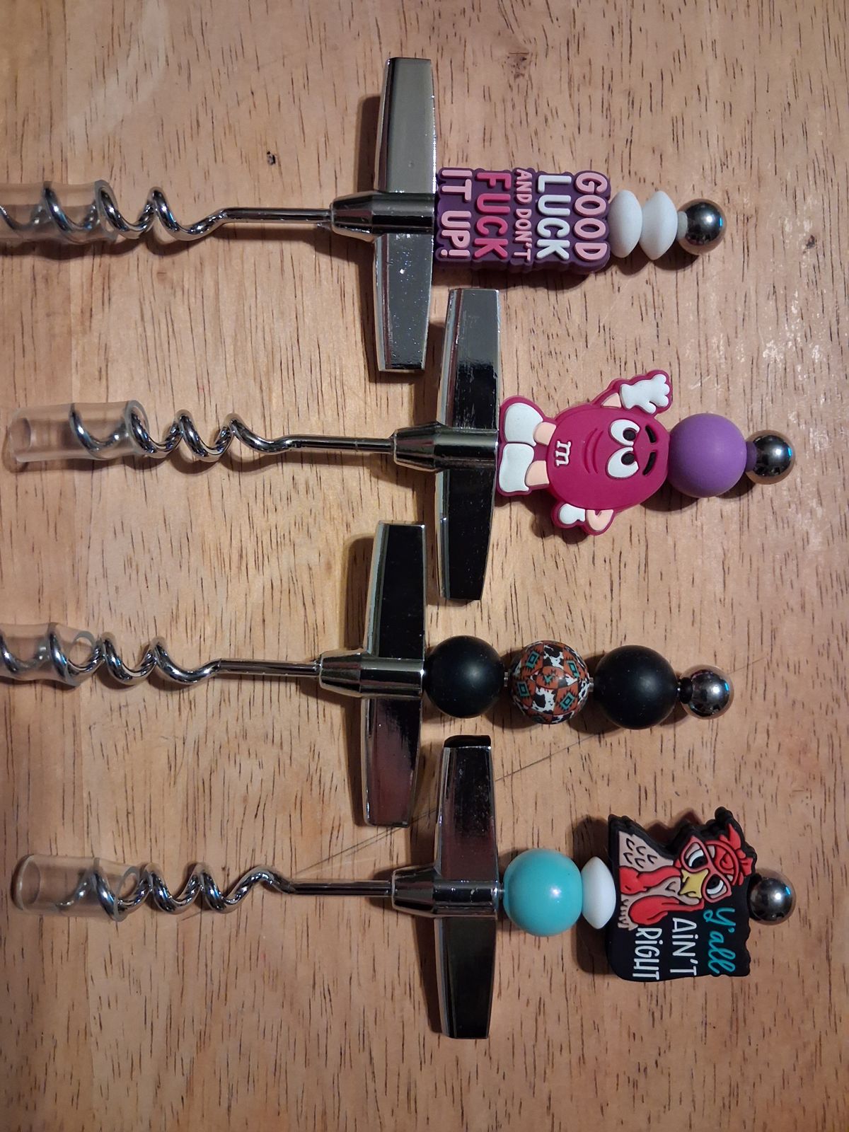 Four silver corkscrews with colorful beaded handles, character charms, and word charms