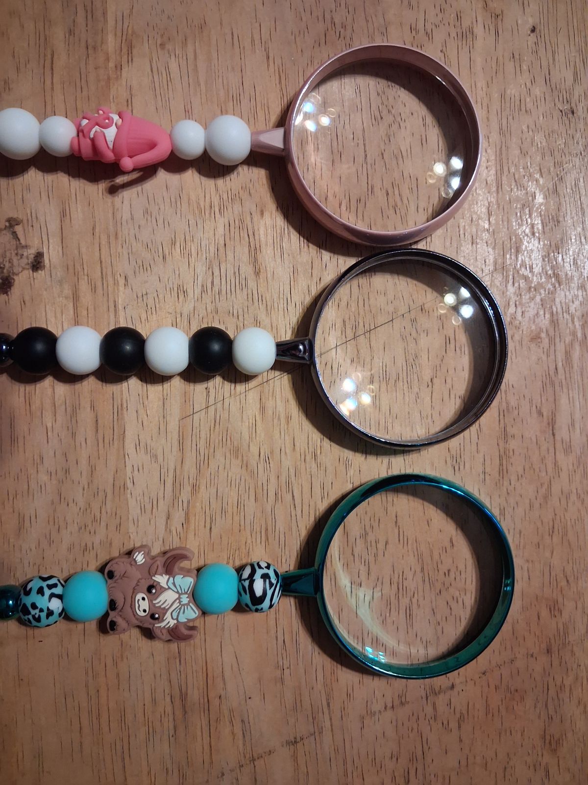 Three magnifying glasses with pink, black and white, and turquoise beaded handles