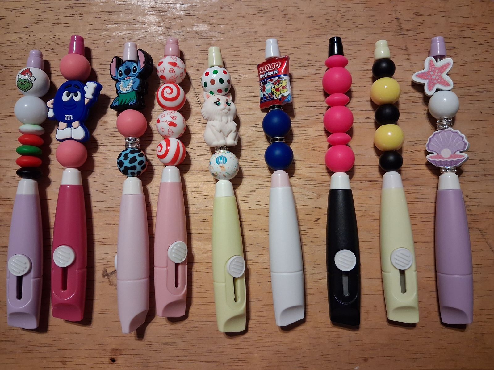 Utility knives in pastel and dark colors with colorful beaded tops and decorative charms
