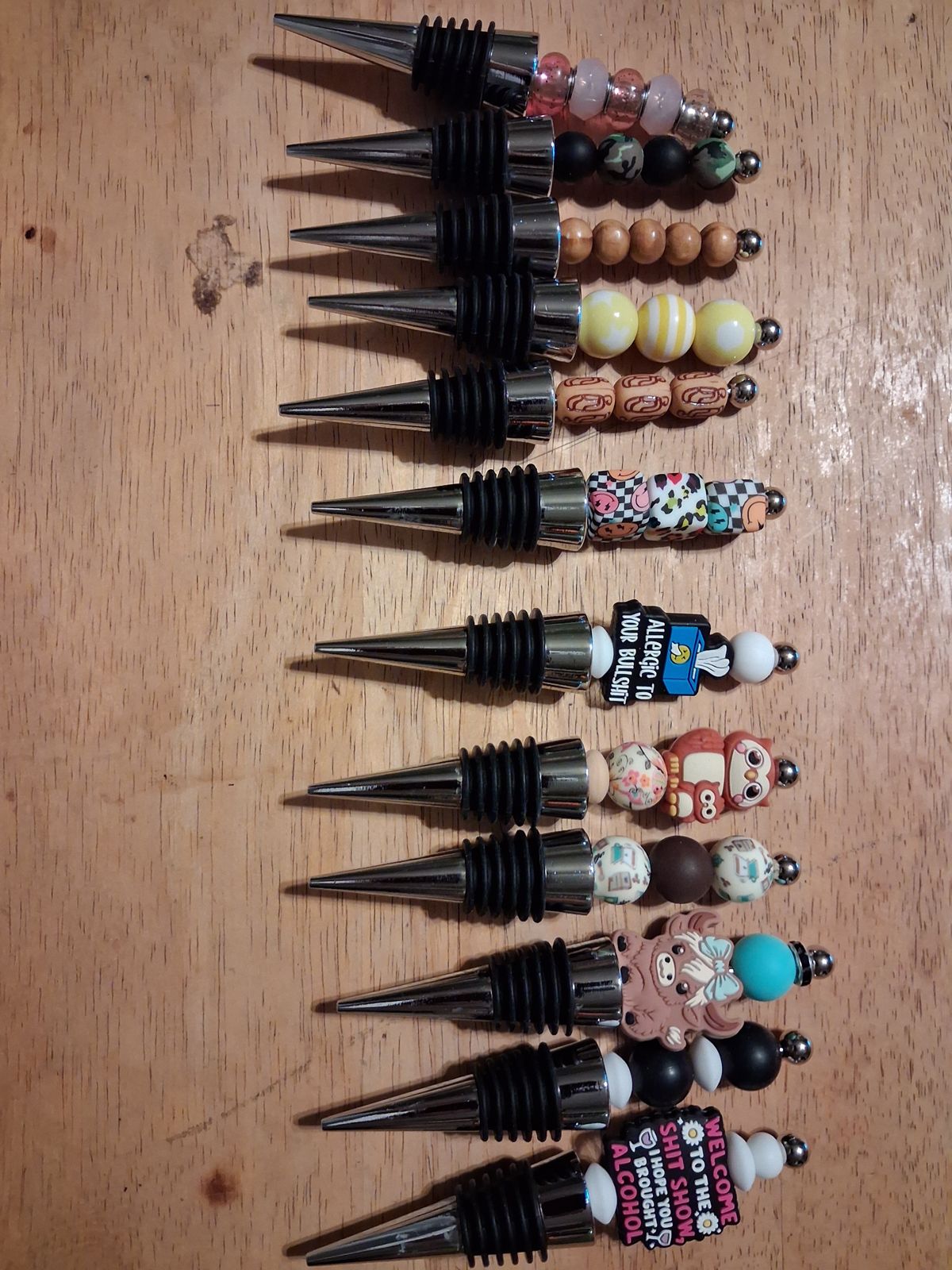 Wine bottle stoppers with colorful and patterned beaded tops and decorative charms