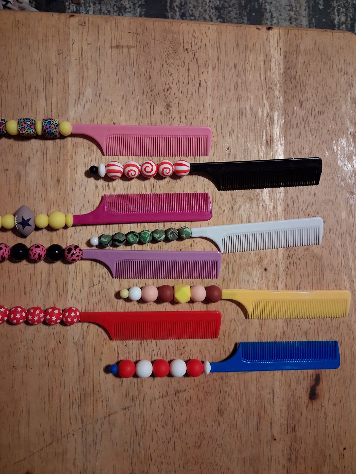 Colorful combs with patterned beaded handles on a wooden table