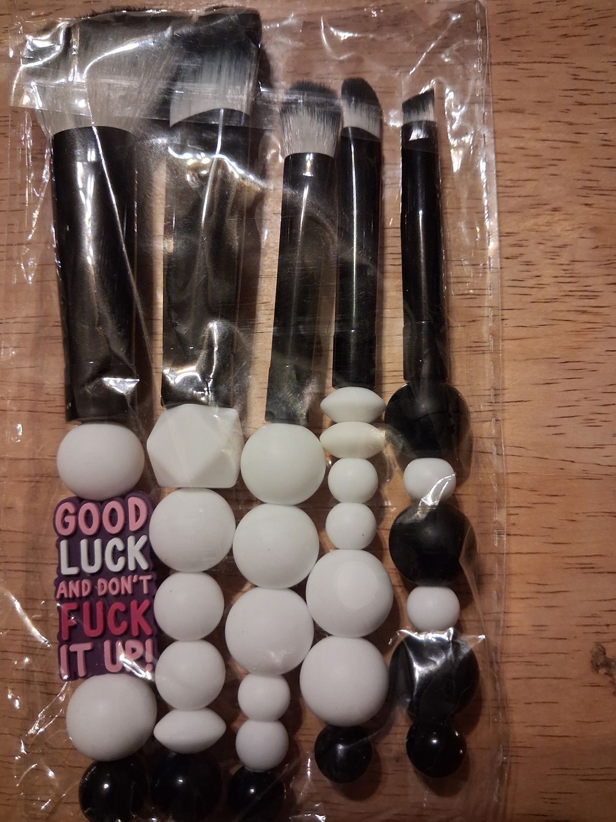 Makeup brushes with black and white beaded handles and a bold word charm
