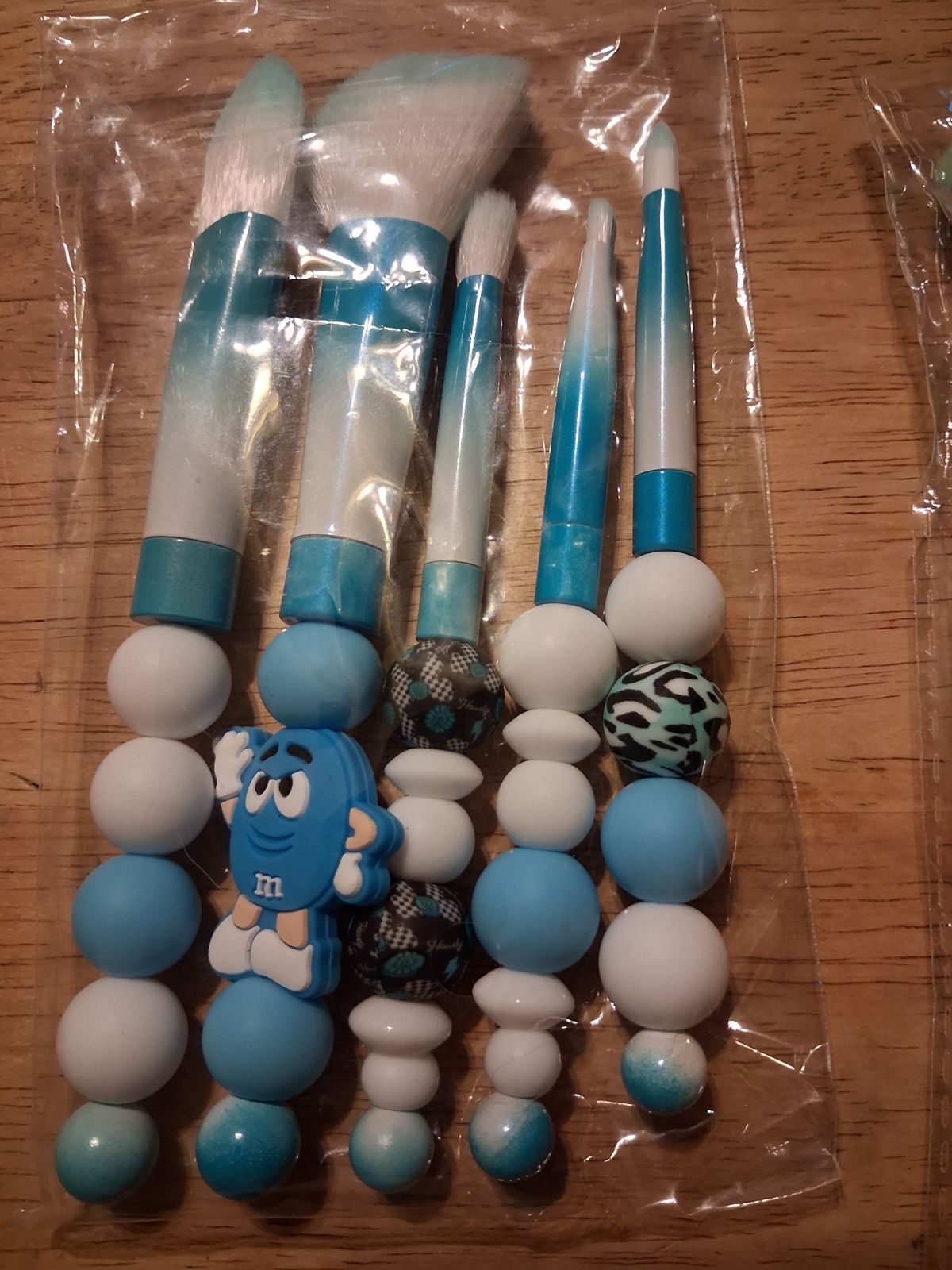 Makeup brushes with blue and white beaded handles and a blue character charm